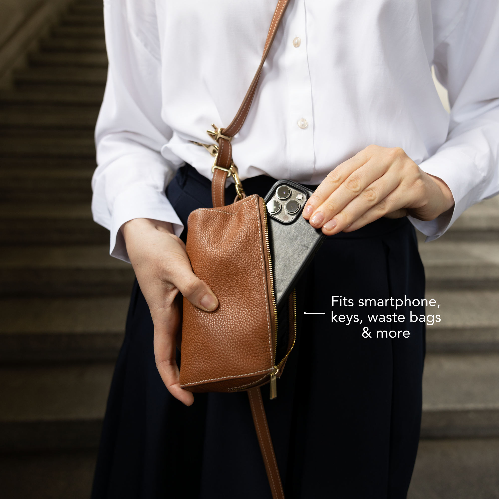 Person holding a brown crossbody bag with text indicating its functionality. #lang_en