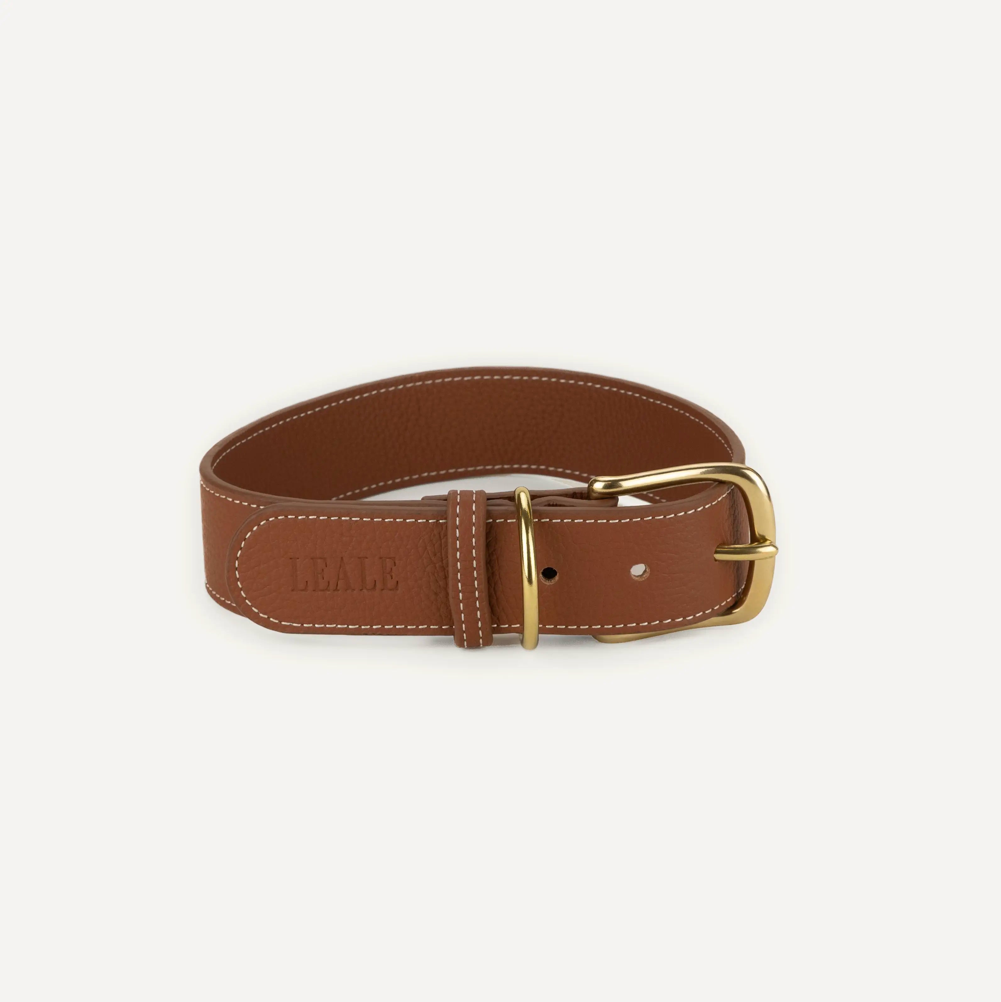 A closeup image of a large leather dog harness in brown, showing full grain leather texture, brass accessories, on a white background