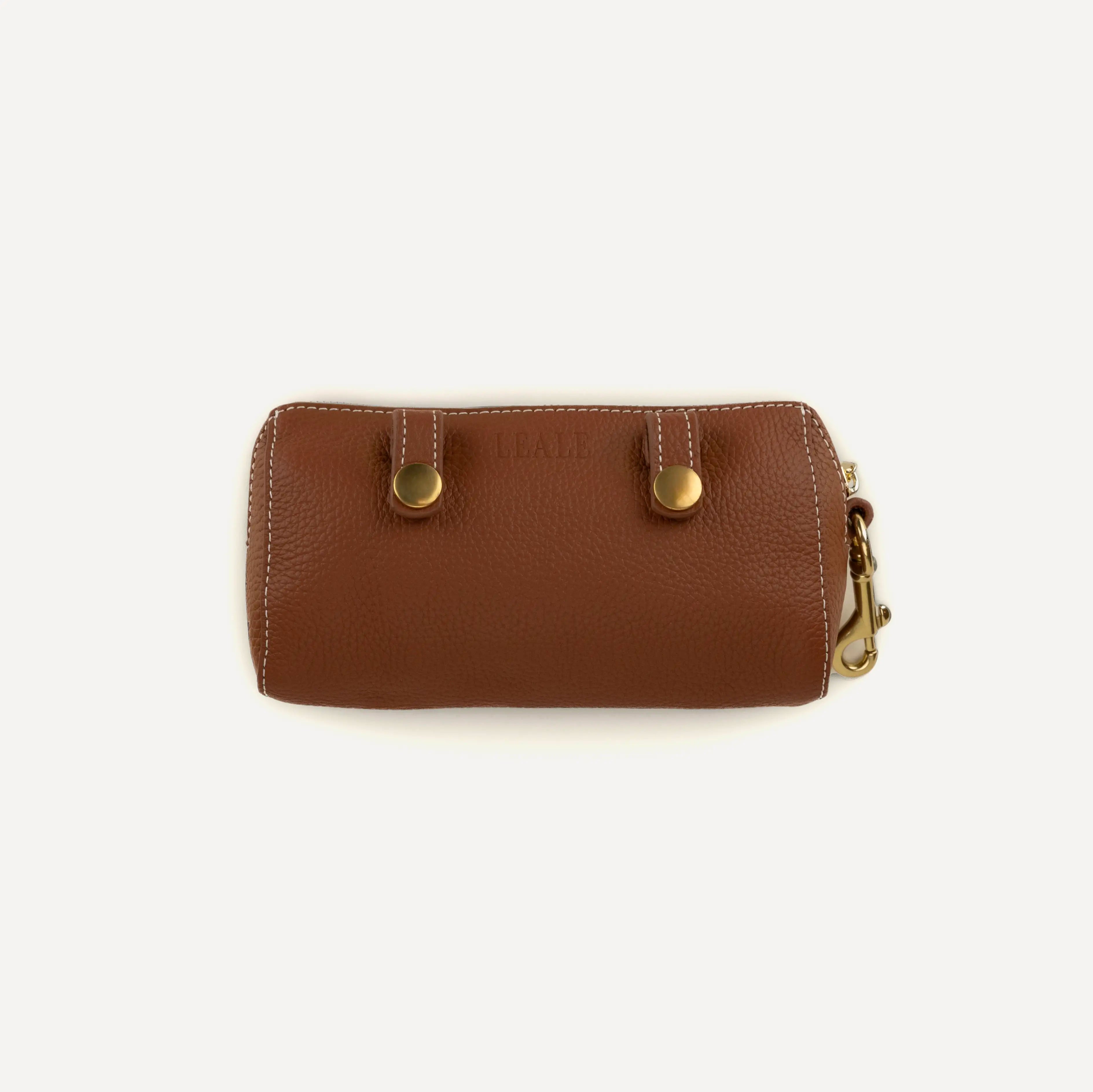 Product image of a leather dog walking bag on a white background, showing product details such as leather texture and brass hardware