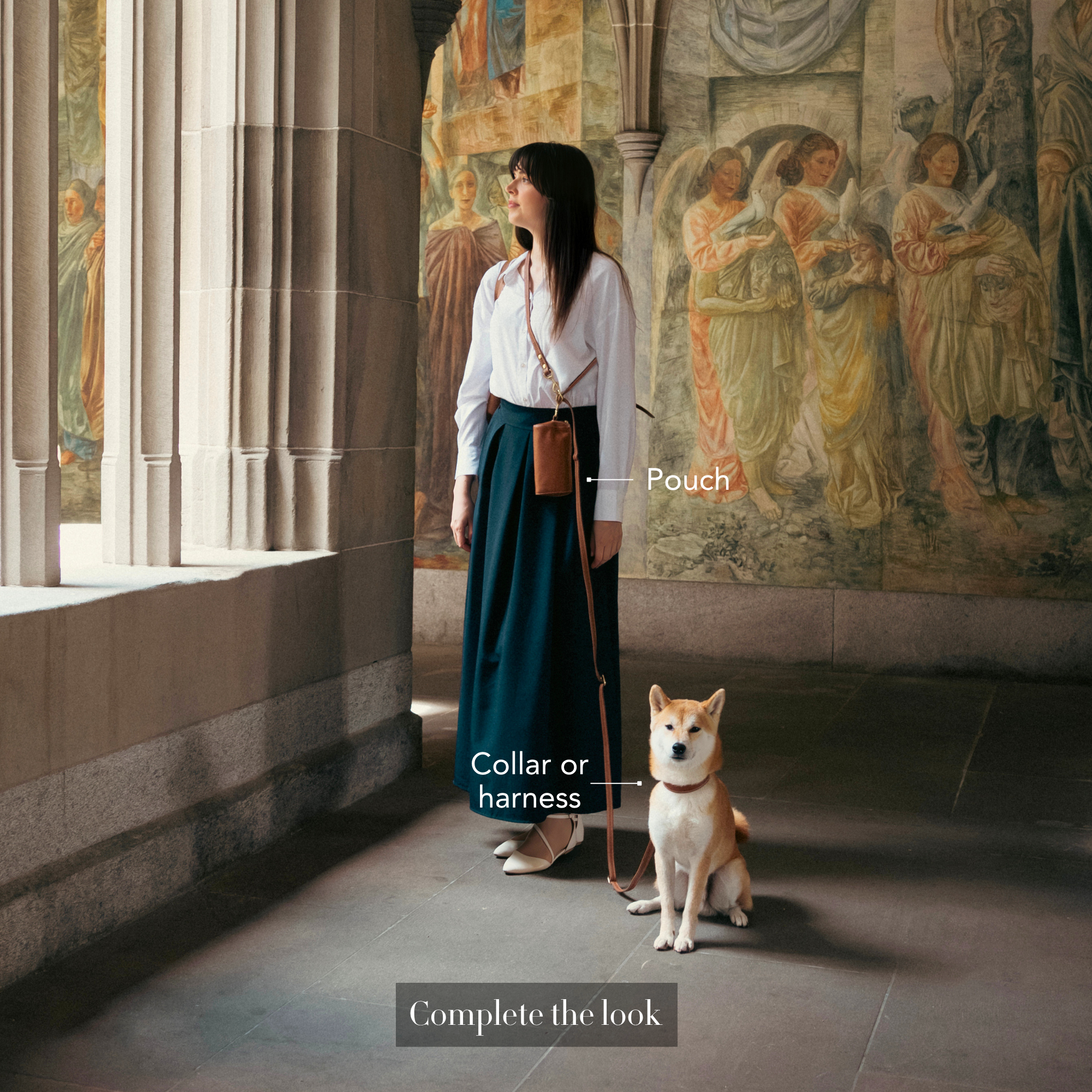 Woman standing with a dog in an ornate hallway with frescoes wearing a crossbody leather dog leash showcasing the LEALE dog walking bundle options with a pouch and collar and harness. #lang_en