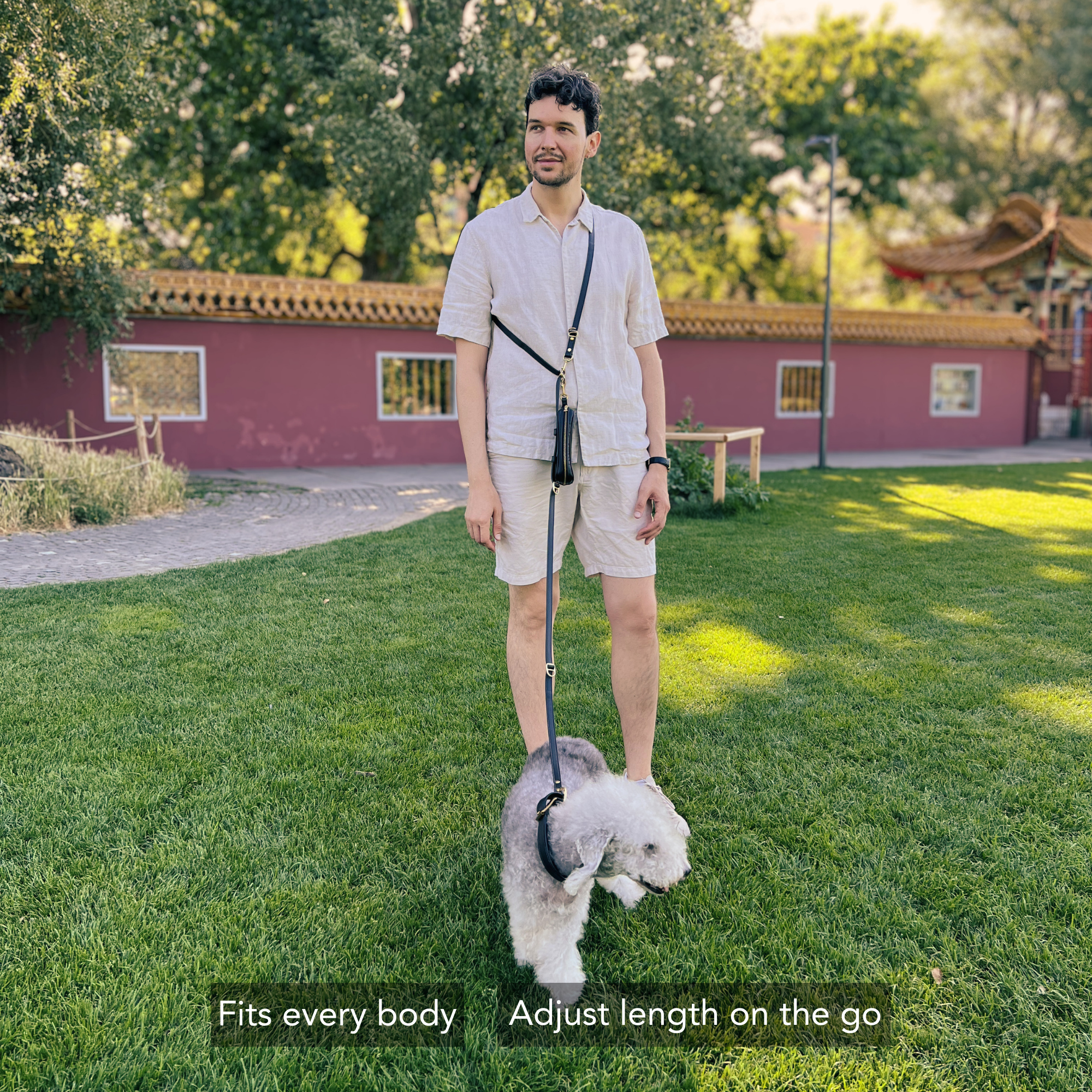 Man walking a dog on a leash in a park with a red building in the background. #lang_en