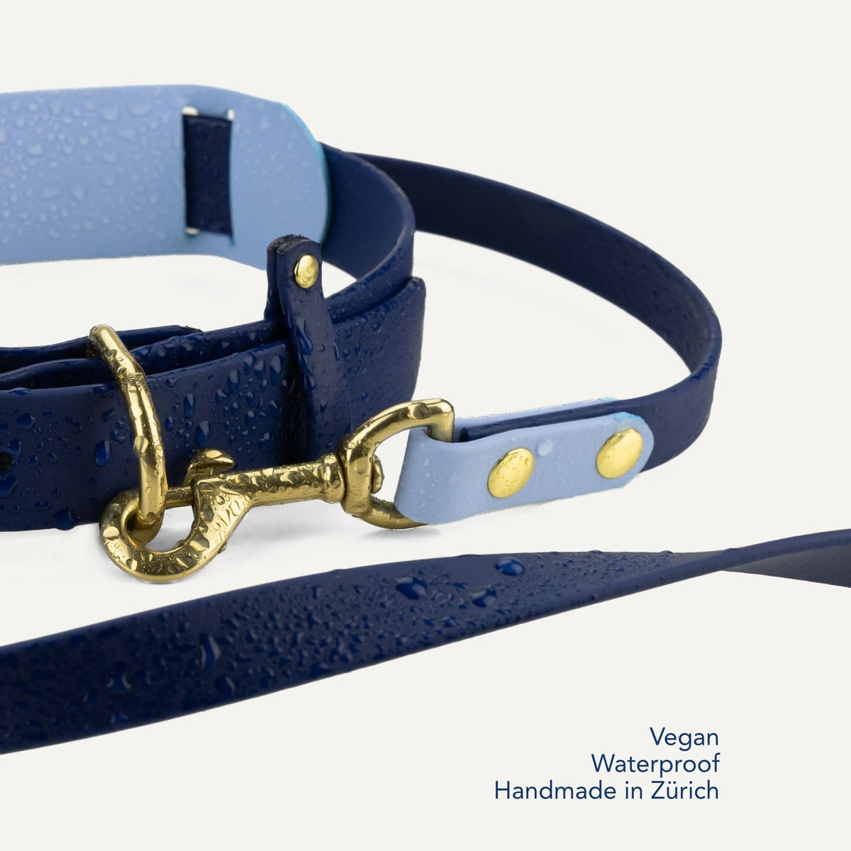 A close-up of a blue vegan leather dog leash with gold-tone hardware, water droplets on the surface, and text in the bottom right corner reading 'Vegan Waterproof Handmade in Zürich'. #lang_en