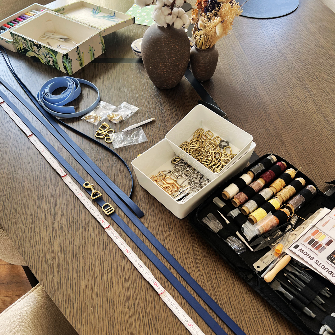 Table with sewing supplies including thread, scissors, and webbing straps for dog leashes.