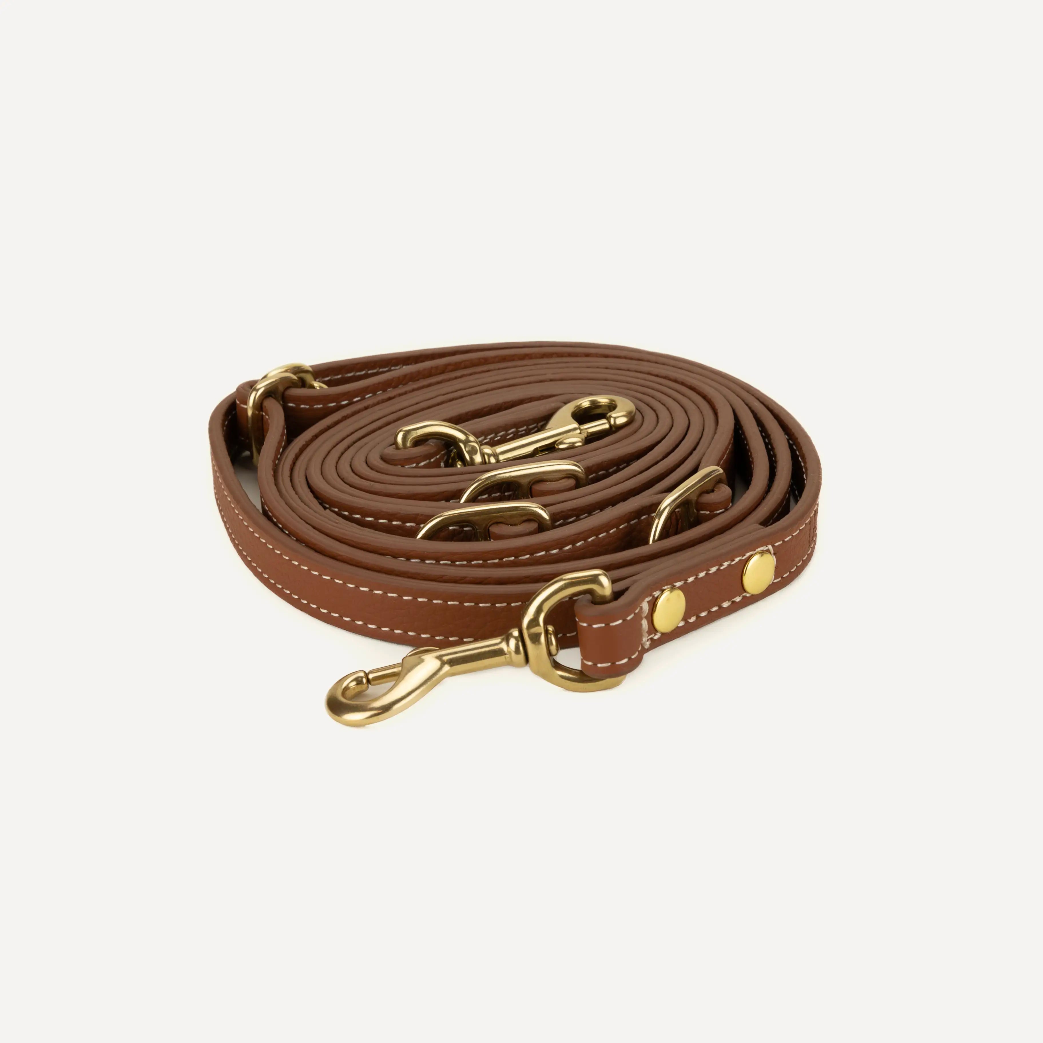 Product image of a leather dog leash rolled up into circle, on a white background