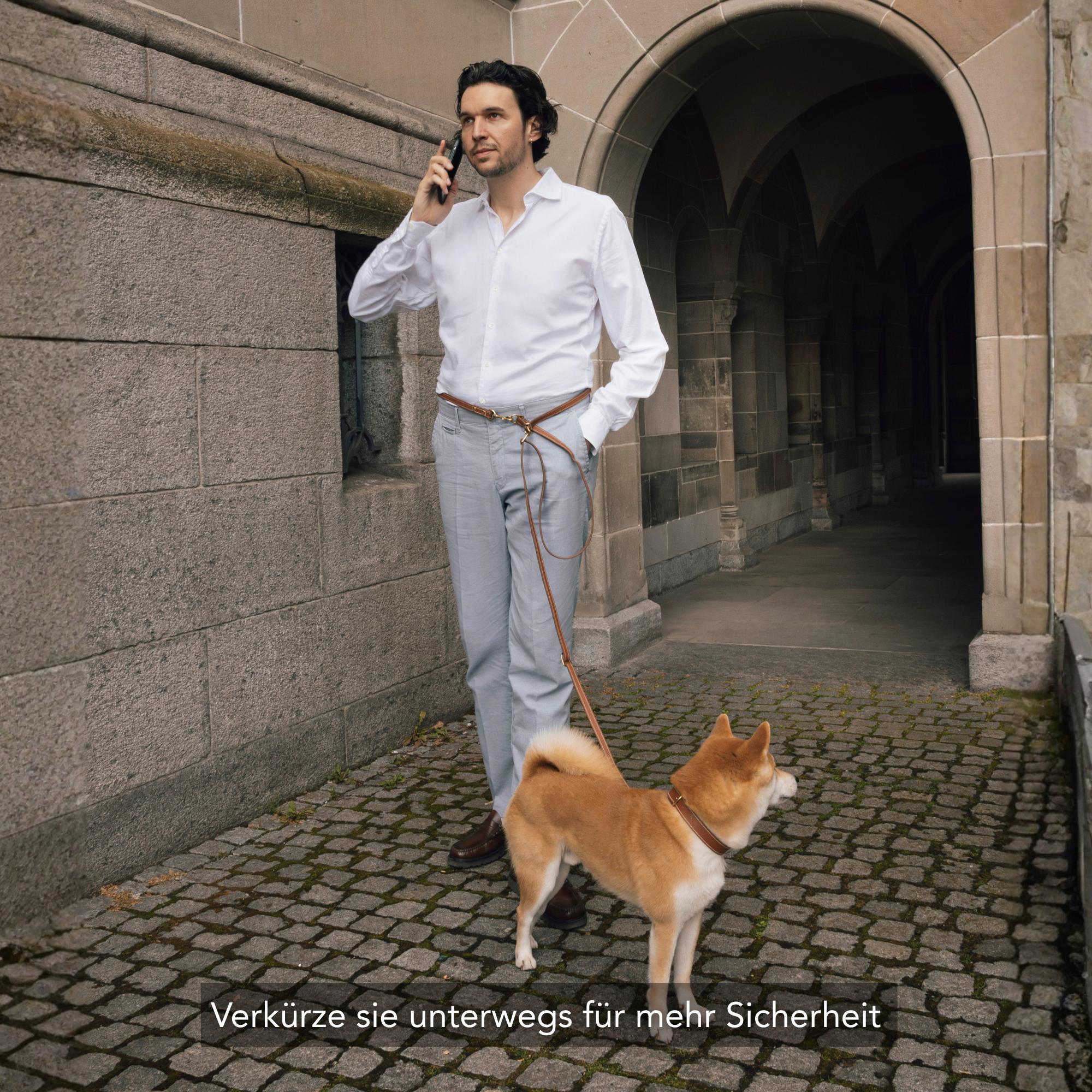 Mann mit einem Shiba Inu Hund und einer braunen Hundeleine in Zürich-Niederdorf, am Telefon. #lang_de