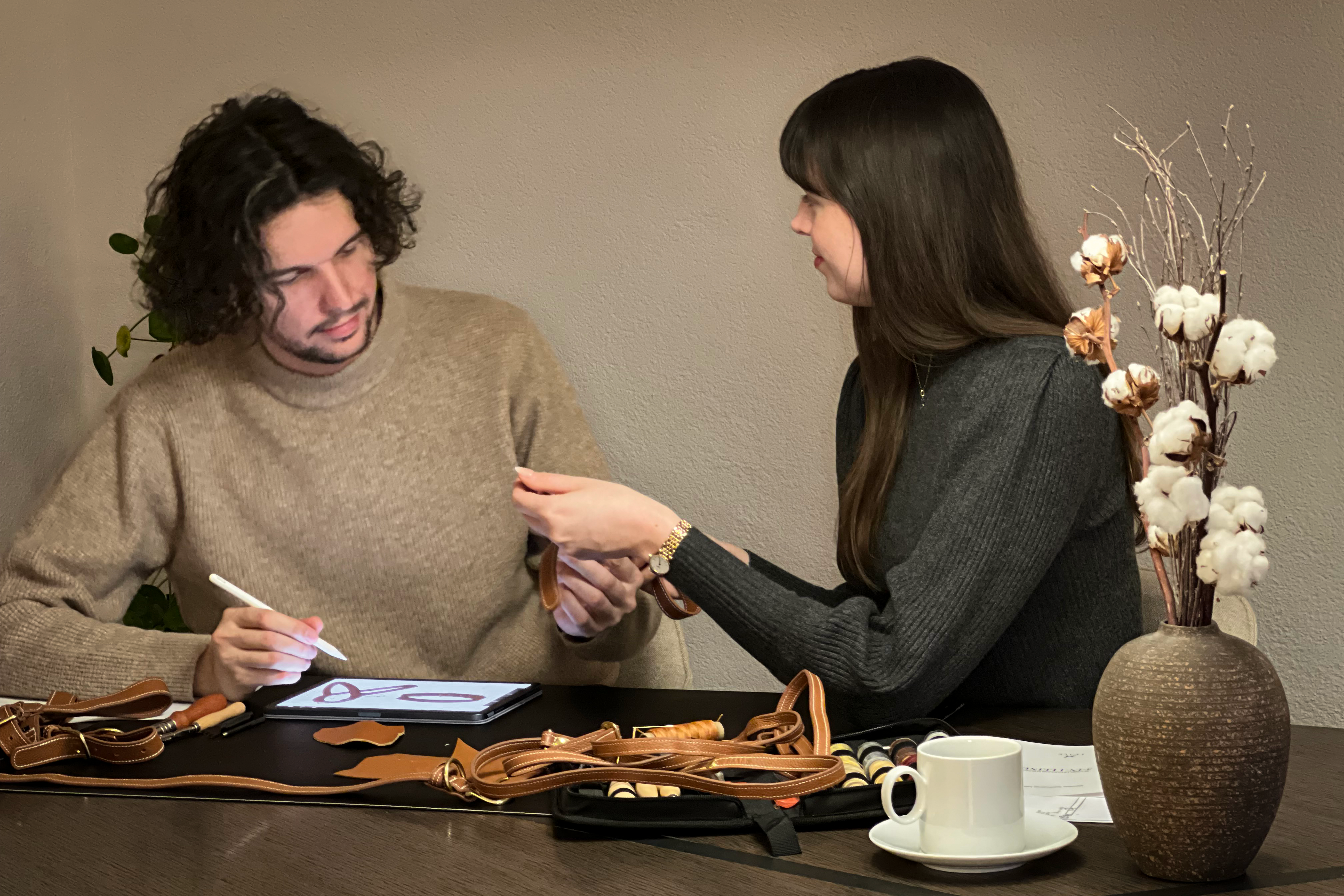 Man and woman sitting at a desk working on leather products for dogs
